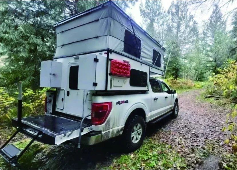 White pickup truck fitted with a TUYU pop-top truck camper parked on a forest track with the roof raised