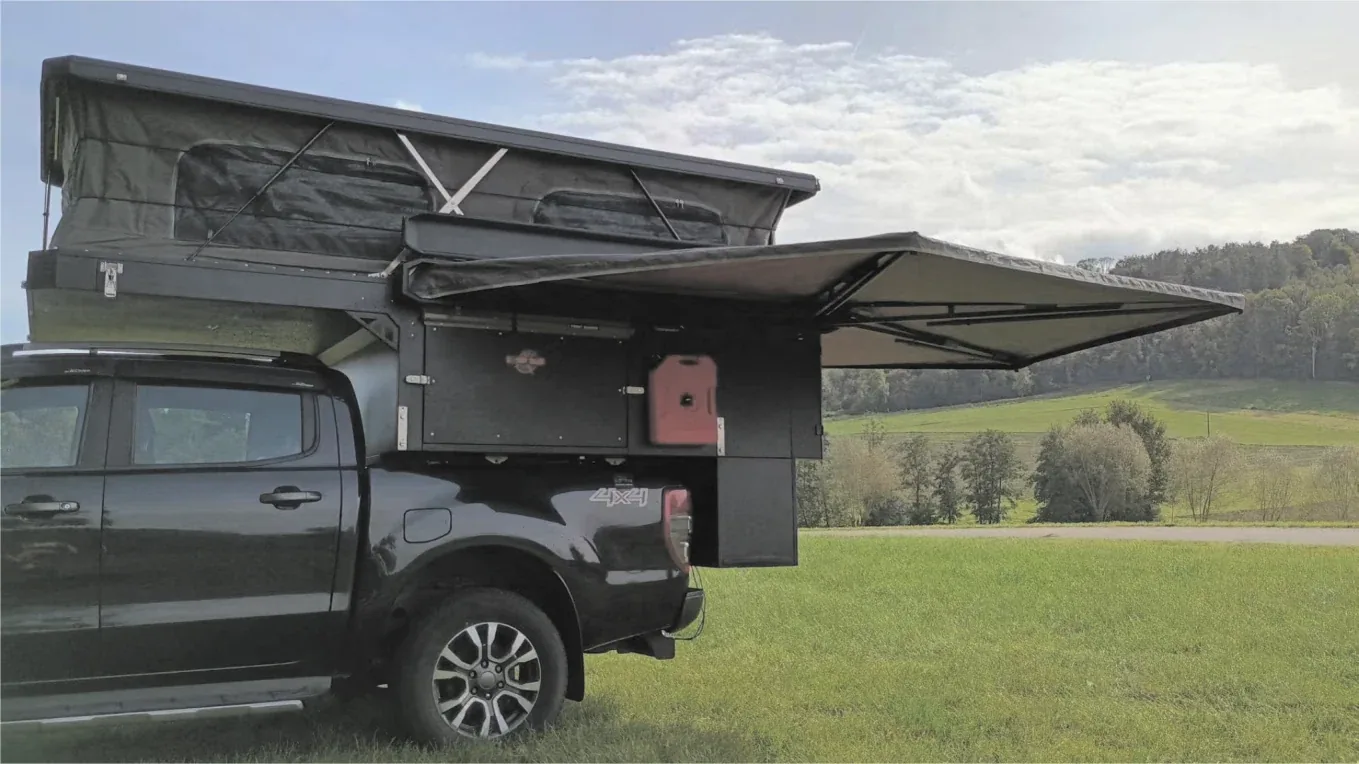 Pickup truck fitted with a TUYU off-road camper with the side awning deployed in open country